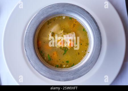 Eine Schüssel Hühnersuppe mit Karotten und Kräutern, Eine einfache, wohltuende Mahlzeit Stockfoto