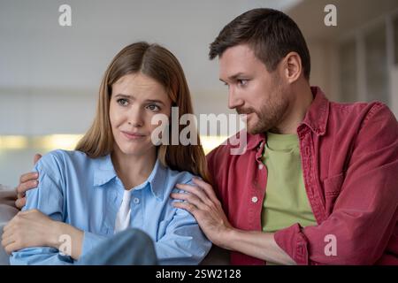 Uneinigkeit in Familienbeziehungen tausendjähriges Paar, entschuldigender Ehemann umarmt beleidigte Frau zu Hause. Stockfoto