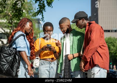 Glücklich interessierte afroamerikanische Freunde nutzen Smartphone Lachen Spaß beim Gehen auf der Straße. Stockfoto