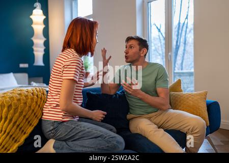 Gestresstes europäisches Millennials-Paar, das sich gefühlsmäßig streitet, während es zu Hause auf dem Sofa sitzt Stockfoto
