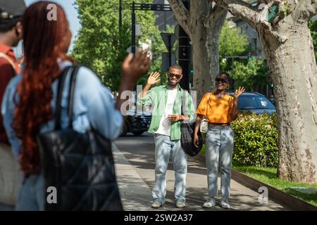 Treffen Sie Freunde für Spaziergänge. Zwei glückliche Studentenpaare sehen sich gegenseitig lächelnd Wellen Hände vor Freude. Stockfoto