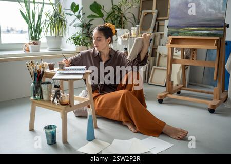 Künstlerische Karriere. Inspirierte, fokussierte Malerin Illustratorin, die mit Aquarellen im Skizzenbuch erstellt. Stockfoto