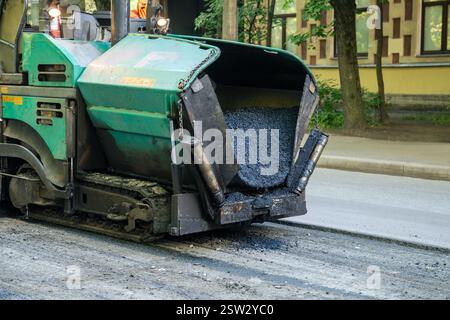 Straßenreparatur, frischer Asphalt vor dem Pflaster. Das Baufahrzeug gießt Asphalt aus Stockfoto