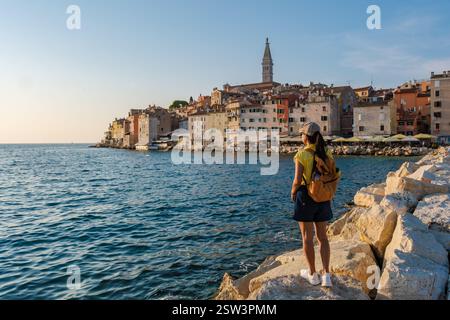 Abendlicher Spaziergang entlang der felsigen Küste von Rovinj, Kroatien mit lebhaften Gebäuden im Hintergrund Stockfoto