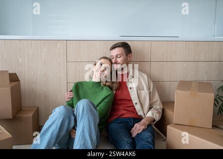 Glückliches Paar Mann Frau, die vom Leben in einer neuen Wohnung träumt, die auf dem Boden sitzt Stockfoto
