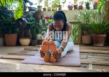 Konzentriert auf gesunde Körper schwarze Frau tun Dehnungsübungen entspannende Muskeln nach der Heimfitness. Stockfoto