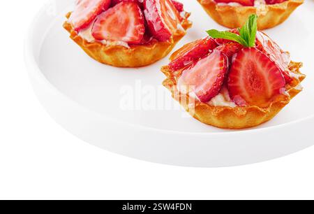 Tartlets mit Vanillepudding, Erdbeeren und Minze auf weißem Teller Stockfoto