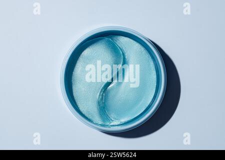 Hydrogel-kosmetische Augenpflaster zur Hautpflege auf blauem Hintergrund. Produkt zur Hautreflechtung, Anti-Aging-Falten. Flecken unter den Augen in einem blauen Behälter. Stockfoto