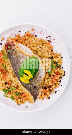 Gegrilltes Lachsfilet mit Kräuter-Couscous auf Teller Stockfoto