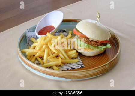 Ein köstlicher Veggie Burger auf einem Brötchen, serviert mit goldenen Pommes frites und Ketchup Stockfoto