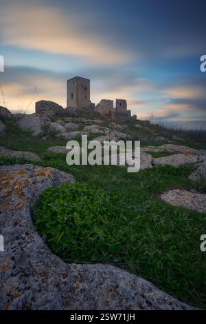 Sonnenuntergang im Schloss von La Estrella, Teba. Der antike Turm auf dem felsigen Gipfel, der dramatische Himmel und das goldene Licht über Andalusien Stockfoto
