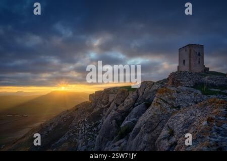 Sonnenuntergang im Schloss von La Estrella, Teba. Der antike Turm auf dem felsigen Gipfel, der dramatische Himmel und das goldene Licht über Andalusien Stockfoto