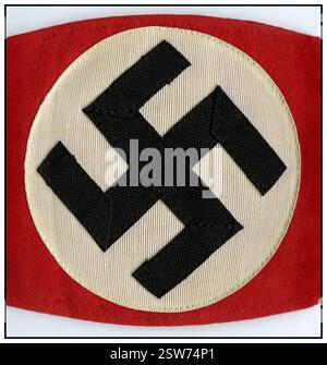 Das Hakenkreuz-Armband ist ein Kleidungsstück mit dem Hakenkreuz – einem Symbol mit alten Wurzeln, das von der NSDAP in den 1930er Jahren und während des Zweiten Weltkriegs berüchtigt wurde. Unter der Herrschaft der Nazis wurde dieses Symbol zu einem Schlüsselelement der Propaganda, das verwendet wurde, um die rassistische und faschistische Ideologie des Regimes zu repräsentieren. Heute ist das Hakenkreuz weithin als Hasssymbol anerkannt, da es mit den abscheulichen Gräueltaten der NS-Zeit in Verbindung gebracht wird Stockfoto