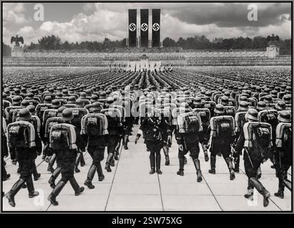 Die Waffen-SS-Truppen der Nürnberger 1930 mit polierten Helmen marschierten in präzisen Reihen zu ihrem Platz bei einer deutschen Nazi-Kundgebung vor dem Zweiten Weltkrieg mit großen Hakenkreuzbändern, die die Arena dominierten Stockfoto