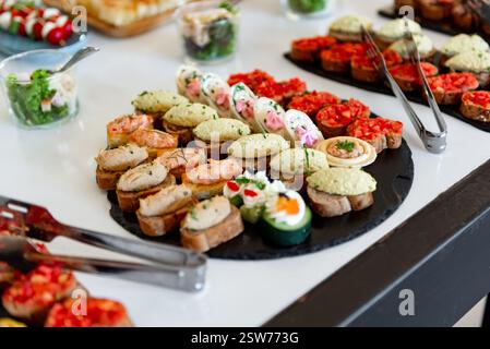Farbenfrohe Kanapees, die kunstvoll auf einem eleganten Display angeordnet sind, laden Gäste zu einer lebhaften Feier ein, die eine Mischung aus Aromen und Texturen für die Gäste bietet Stockfoto