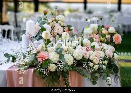 Üppige, florale Mittelstücke mit zarten rosa und weißen Blüten schaffen ein romantisches Ambiente bei einem Hochzeitsempfang im Freien in einem ruhigen Garten, Showcas Stockfoto