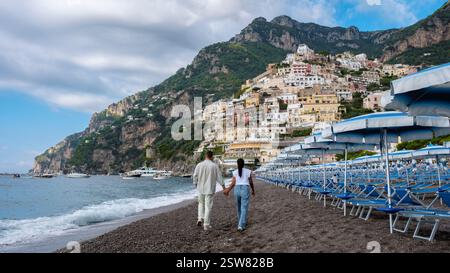 Ein paar Spaziergänge Hand in Hand am Strand der Amalfiküste unter dramatischem Himmel entlang Stockfoto