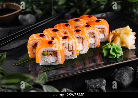 Philadelphia Sushi-Brötchen werden auf schwarzem Teller mit Wasabi und Ingwer serviert Stockfoto