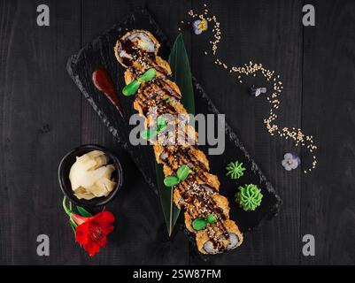 Tempura Maki Sushi-Brötchen mit Sesamsamen und Unagi-Sauce auf schwarzem Steinteller Stockfoto