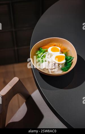 Dampfende Hühnernudelsuppe mit Eiern auf dem Restauranttisch Stockfoto