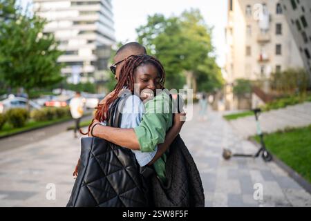 Glückliche schwarze Frau begrüßt den Mann mit einem Lächeln, Familientreffen draußen. Geschwister treffen sich Stockfoto