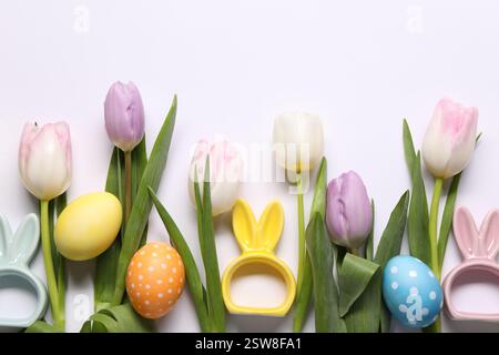 Ostereier, schöne Tulpen und Hasenfiguren auf weißem Hintergrund, flache Lay Stockfoto