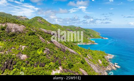 Blick aus der Vogelperspektive auf grüne Inseln mit felsigen Küsten, umgeben vom riesigen blauen Ozean. Seychellen, Mahe. Stockfoto