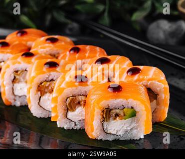 Philadelphia Sushi-Brötchen werden auf schwarzem Teller mit Wasabi und Ingwer serviert Stockfoto