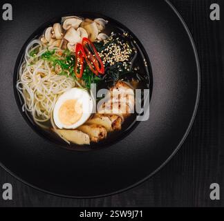 Dampfschüssel mit Hähnchenramen auf schwarzem Tisch Stockfoto