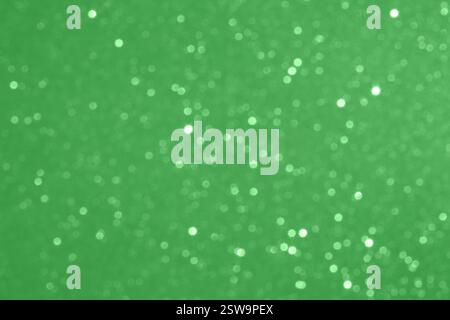 Grüner, defokussierter Glitzer-Bokeh-Hintergrund mit funkelnden und schimmernden Partikeln Stockfoto