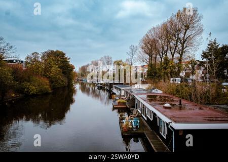 Hausboote treiben friedlich auf dem ruhigen niederländischen Kanal, reflektieren den ruhigen Himmel und schaffen eine perfekte Harmonie zwischen Wasser, Natur und Ruhe Stockfoto