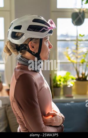 Nahaufnahme Porträt einer hübschen Radfahrerin, die zu Hause Helm und Sportbrille trägt. In Profil anzeigen Stockfoto