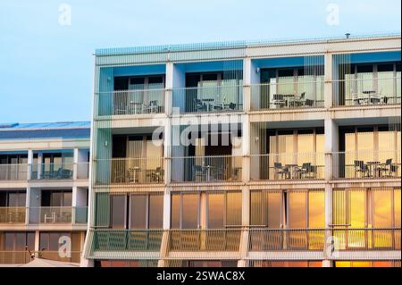 Muster der Balkone des Hotelzimmers in einem modernen Gebäude mit warmem Sonnenuntergangslicht, das auf die Fassade fällt Stockfoto