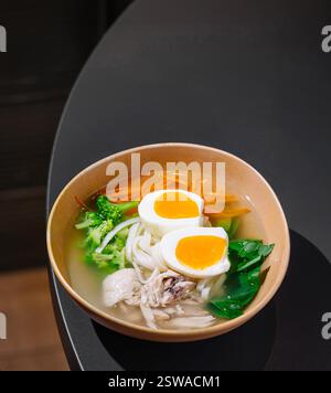 Dampfende Hühnernudelsuppe mit Eiern auf dem Restauranttisch Stockfoto