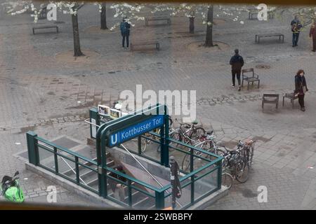 Fußgänger und Fahrräder in der Nähe des U-Bahn-Eingangs am Bahnhof Kottbusser Tor in Berlin. Leute laufen, Fahrräder parken und ein Motorrad. Stockfoto