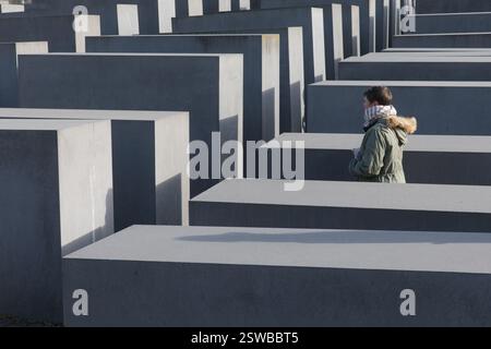 Tourist am Holocaust-Mahnmal, Berlin. Eine Person steht zwischen den Betonblöcken. Eine düstere Hommage an die Opfer. Stockfoto