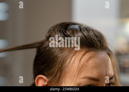 Haarfärbeprozess mit detailliertem Fokus auf Haarwurzeln und Haarsträhnen unter Lichtverhältnissen in Innenräumen Stockfoto