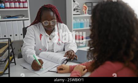 Weibliche Ärztin berät mit Patienten im Krankenhaus Raum während der Überprüfung medizinischer Dokumente drinnen mit professionellem Fokus und unterstützendem Inter Stockfoto