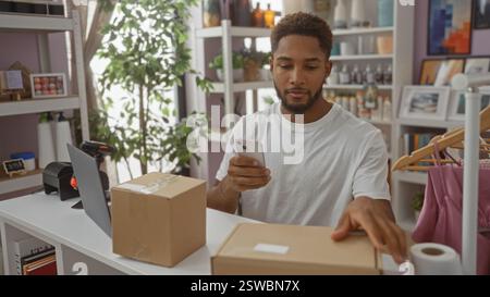 Junger Mann in einem Haus-Dekorationsgeschäft, der ein Smartphone benutzt, um Pakete an einer Theke zu verwalten, die von Pflanzen und Dekorationen umgeben ist Stockfoto