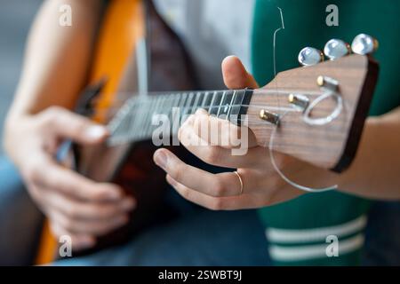 Die Hände der Musikerin drücken die Bünde auf die Balalaika, stimmen den Ton und spielen Melodie mit Fokus, Reimsatz gesetzt Stockfoto