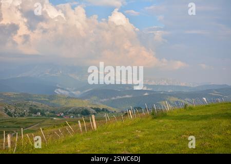 Sanfte Hügel und majestätische Berge, die sich bis in den Horizont unter einem teilweise bewölkten Sommerhimmel erstrecken Stockfoto
