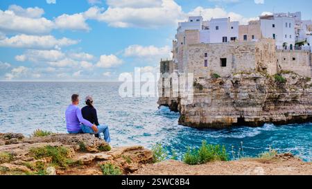 Ein Paar, das den wunderschönen Blick auf die Küste von Polignano a Mare, Apulien, unter einem bewölkten Himmel bewundern kann Stockfoto