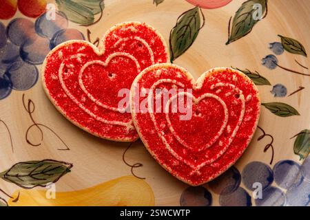 Zwei herzförmige Zuckerkekse zum Valentinstag auf einem dekorativen Teller. Stockfoto