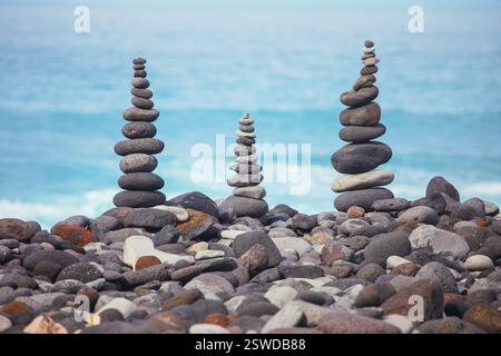 Steintürme stehen hoch und zeugen von Präzision und Geduld, die erforderlich sind, um an felsigen Ufern ein Gleichgewicht zu erreichen. Stapel von ausgeglichenen Steinen unterschiedlicher Größe Stockfoto