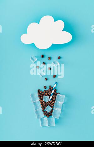 Wolkenförmige Papierkartennotiz und Regen und Tasse Kaffee aus Kaffeebohnen und Eiswürfeln auf blauem Hintergrund. Kreatives Wetter minimales Konzept. Stockfoto