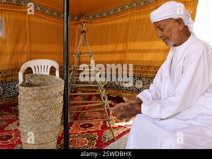 Dibba Al Baya. Februar 2025. Ein omanischer Mann in traditioneller Kleidung präsentiert traditionelles Kunsthandwerk auf einem Kulturfestival in Dibba Al-Baya, Gouvernement Musandam, Oman, am 20. Februar 2025. Quelle: Yang Yiran/Xinhua/Alamy Live News Stockfoto