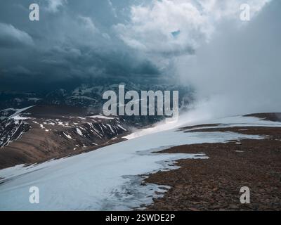 Wundervolle dramatische Landschaft mit großen schneebedeckten Berggipfeln über niedrigen Wolken. Schneesturm auf einem Berg. Atmosphärisch groß Stockfoto