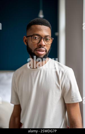 Seriöser junger afroamerikanischer Hausbesitzer, der sich in der Wohnung posiert Stockfoto