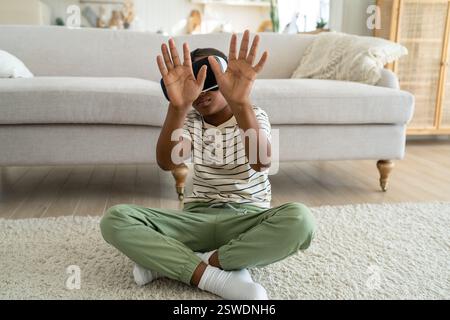 Ein kleiner, neugieriger afroamerikanischer Junge mit VR-Brille, der Zeit in der virtuellen Welt verbringt Stockfoto