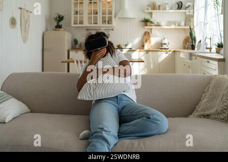 Schockierte afroamerikanische Frau mit Virtual-Reality-Brille hat Angst, wenn sie sich Horror-VR-Videos ansieht Stockfoto